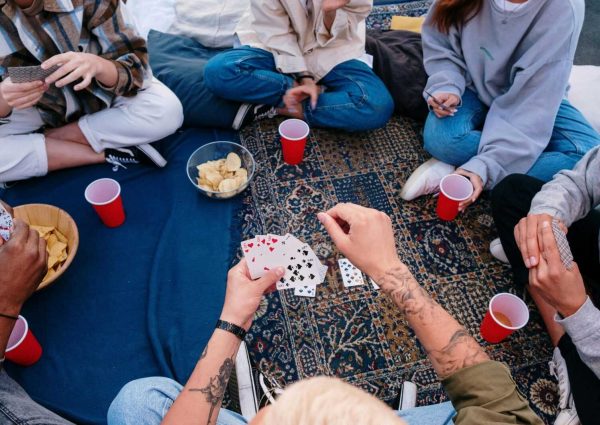 pexels-photo-4881627-4881627 Friends enjoying a card game outdoors on a picnic blanket, sharing snacks and drinks.